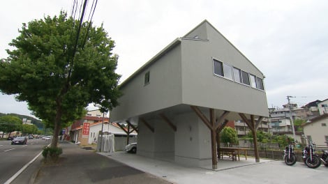 幹線道路沿いに建つ、高床式の家